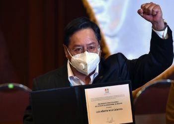 Bolivian President-elect Luis Arce raises his clenched fist as he poses with his credentials after getting them from the president of the Bolivian Supreme Electoral Tribunal (TSE) Salvador Romero (out of frame) at the Central Bank's auditorium in La Paz on October 28, 2020. (Photo by AIZAR RALDES / AFP)