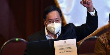 Bolivian President-elect Luis Arce raises his clenched fist as he poses with his credentials after getting them from the president of the Bolivian Supreme Electoral Tribunal (TSE) Salvador Romero (out of frame) at the Central Bank's auditorium in La Paz on October 28, 2020. (Photo by AIZAR RALDES / AFP)