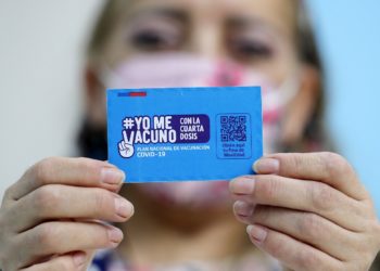 A person shows a vaccination card for the coronavirus disease COVID-19 at a vaccination centre in Santiago, on 10 January 2022. - Chile started administering today a fourth COVID-19 vaccine dose to people over the age of 12 with weakened immune systems. (Photo by Javier TORRES / AFP)