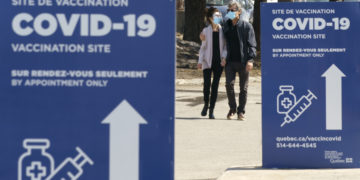 A couple leaves a COVID-19 vaccination clinic in Montreal, on Tuesday, March 23, 2021. THE CANADIAN PRESS/Paul Chiasson