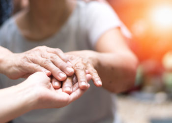 Geriatric doctor or geriatrician concept. Doctor physician hand on happy elderly senior patient to comfort in hospital examination room or hospice nursing home or wellbeing county.