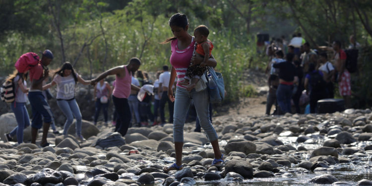 A woman carrying a child walks across the Tachira river on the outskirts of Cucuta, on the Colombian-Venezuelan border, Colombia February 25, 2019. REUTERS/Marco Bello