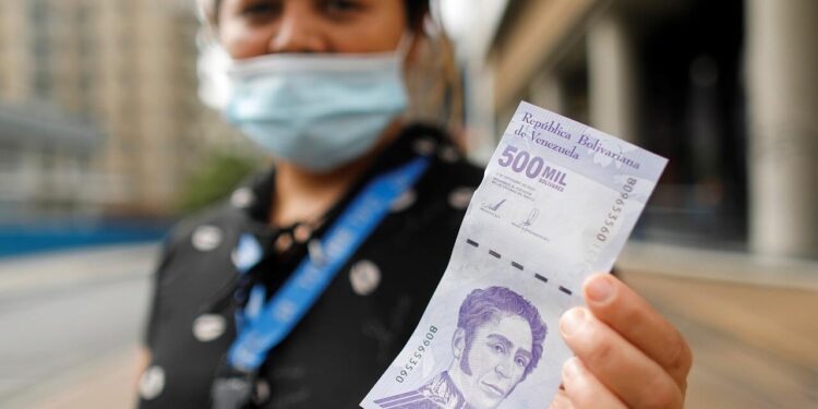 A woman shows a banknote of 500,000 bolivars, worth just 25 U.S. cents at the current exchange rate, in Caracas, Venezuela March 16, 2021. REUTERS/Leonardo Fernandez Viloria NO RESALES. NO ARCHIVES