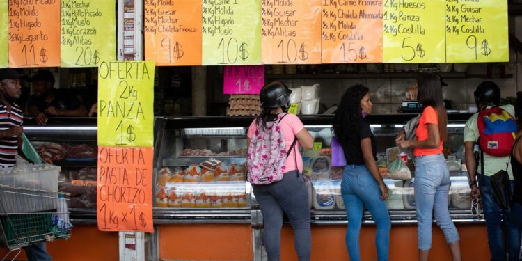 AME9701. CARACAS (VENEZUELA), 02/07/2021.- Varias personas compran en una carnicería el 25 de junio de 2021, en Caracas (Venezuela). Venezuela lleva inmersa en la pesadilla de la hiperinflación desde noviembre de 2017, una época de cifras mareantes que ha derivado en una dolarización espontánea como boya de salvación. Sin embargo, en los últimos meses, el incremento de los precios ha comenzado a frenarse, lo que alimenta la esperanza de dejar atrás el mal sueño. EFE/ Rayner Peña R